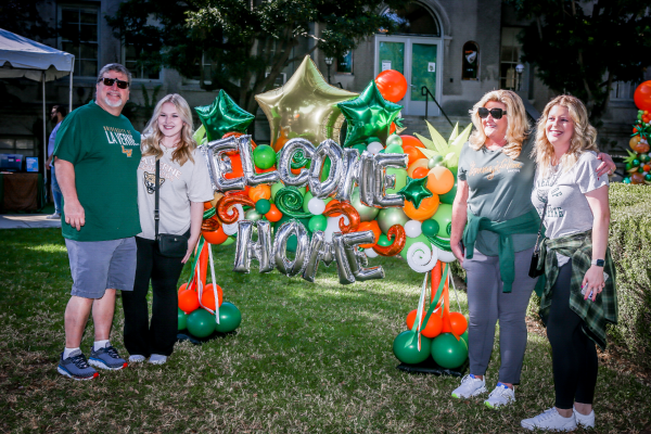 Family standing in front of a "Welcome Home" sign at Homecoming Weekend