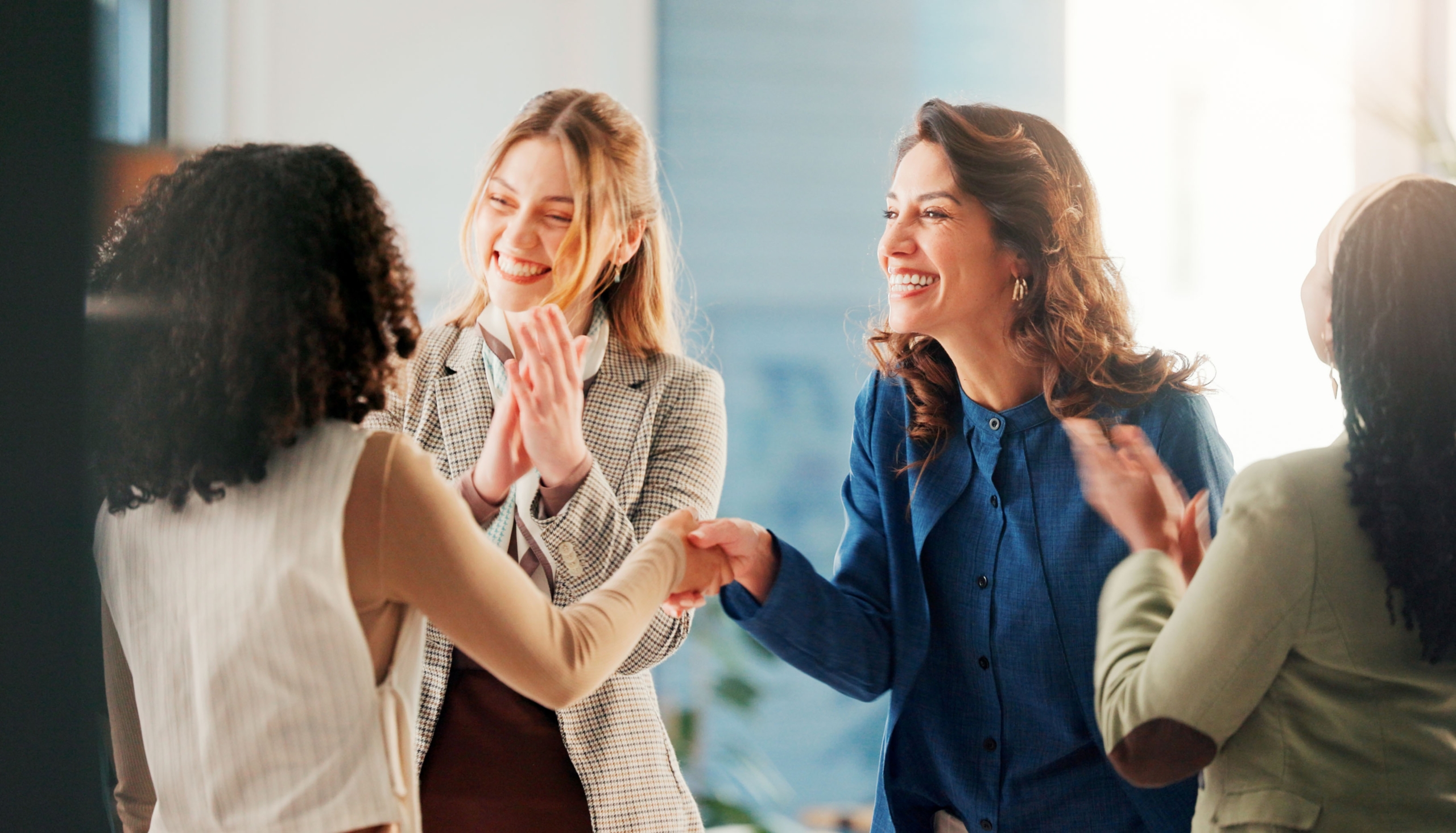 Group of women handshaking and clapping.
